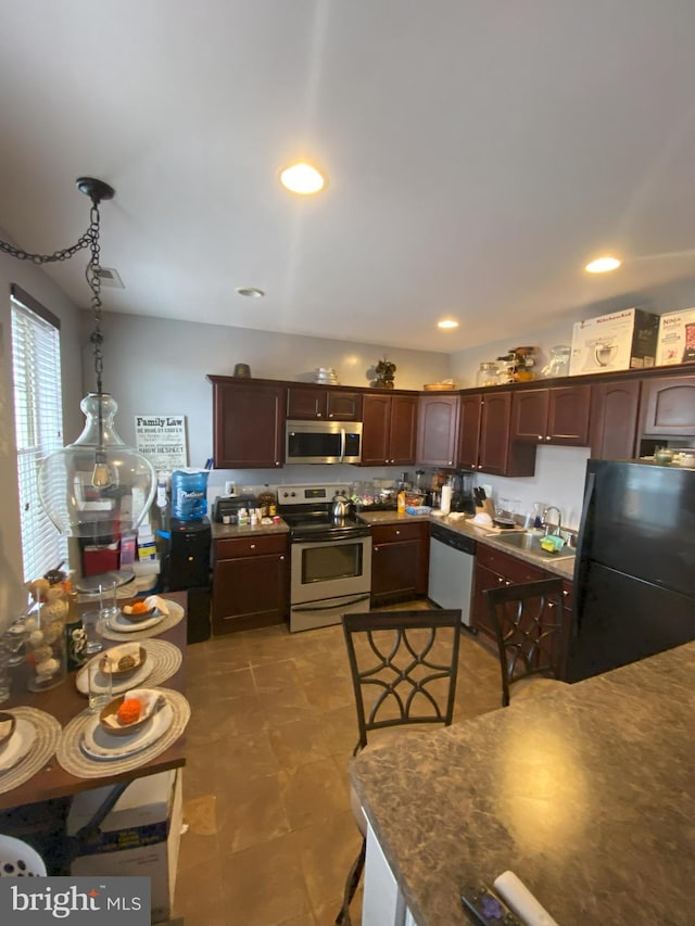 kitchen with stainless steel appliances, dark brown cabinets, sink, and pendant lighting