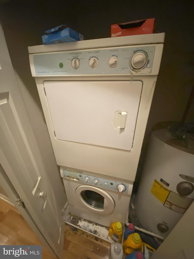 washroom featuring stacked washer / dryer, wood-type flooring, and water heater