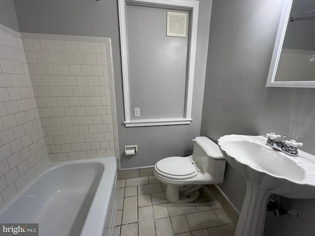 bathroom with tile patterned flooring, tiled shower / bath combo, and toilet