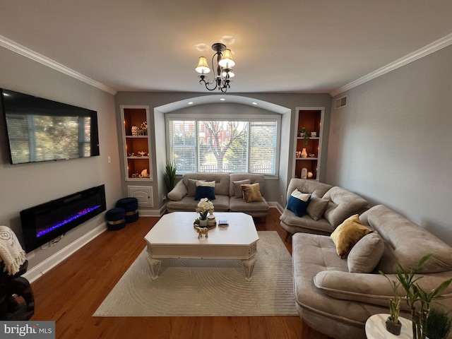 living room with ornamental molding, hardwood / wood-style floors, a chandelier, and built in shelves