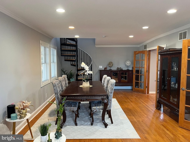 dining space with french doors, ornamental molding, and light hardwood / wood-style floors