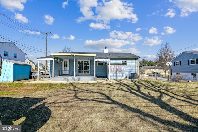 back of property featuring a porch, central AC, fence, and a lawn