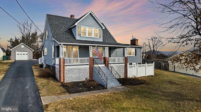 bungalow featuring a yard, a garage, an outdoor structure, and covered porch