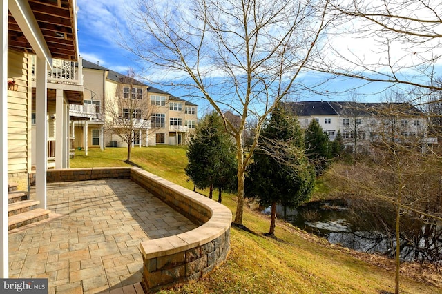 view of property's community with a patio, a water view, and a lawn