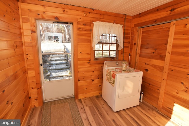 laundry area with laundry area, washer / clothes dryer, wood walls, and light wood-style flooring