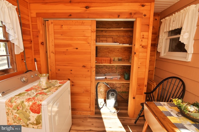 interior space with light wood finished floors, separate washer and dryer, and wooden walls