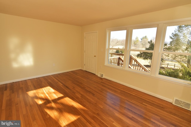 unfurnished room with visible vents, baseboards, and wood finished floors