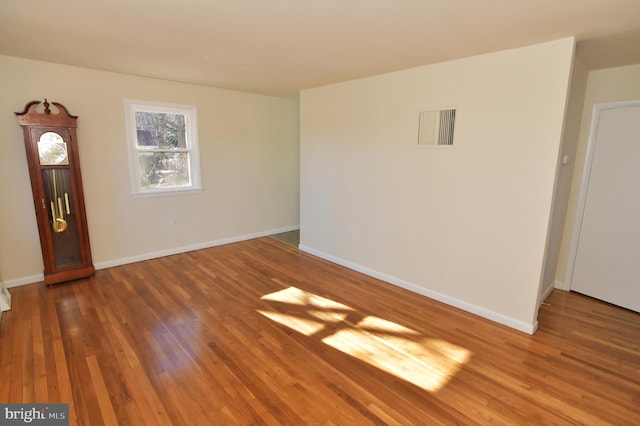 unfurnished room featuring visible vents, dark wood finished floors, and baseboards