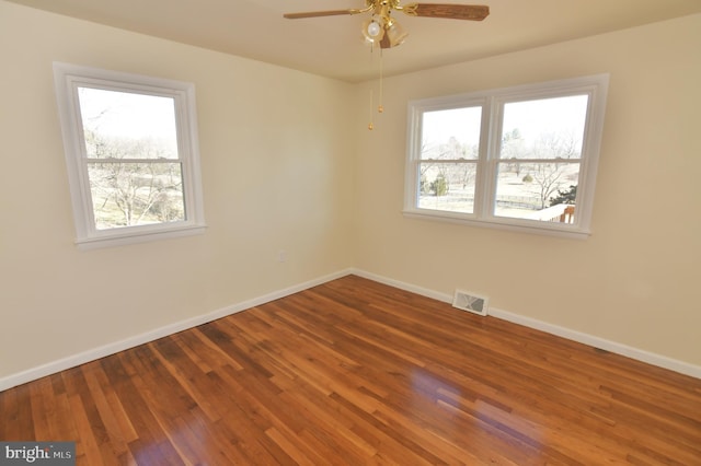 unfurnished room with baseboards, visible vents, ceiling fan, and wood finished floors