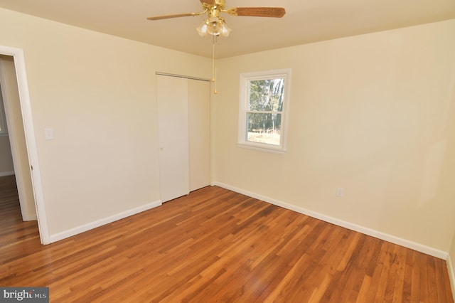 unfurnished bedroom with a closet, ceiling fan, baseboards, and wood finished floors