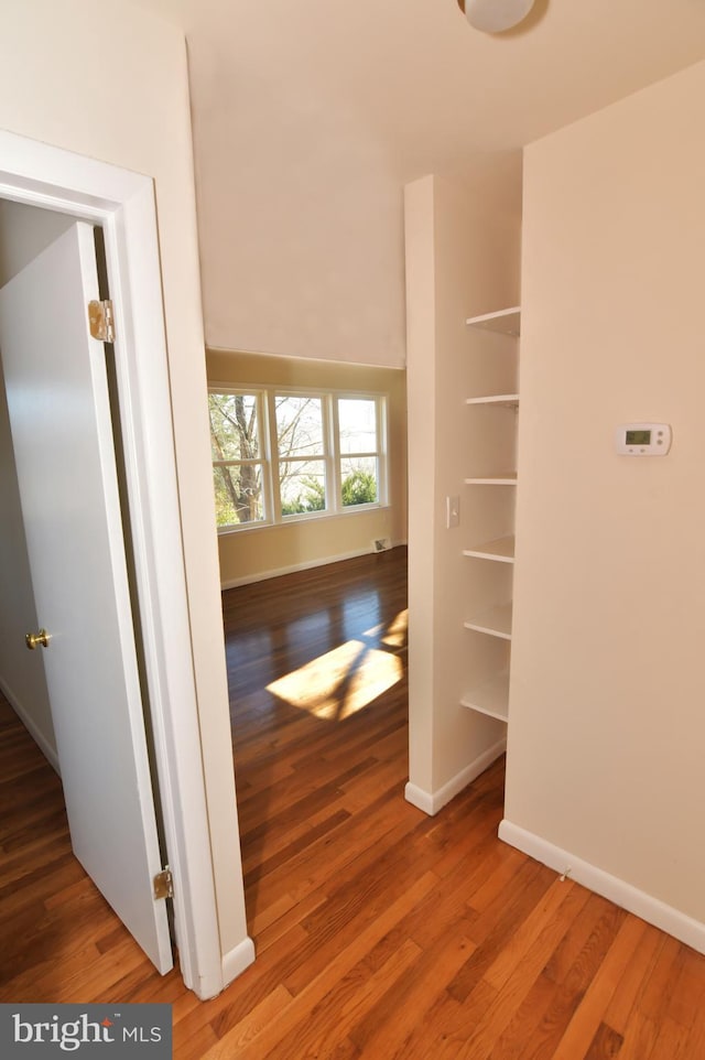 hallway featuring baseboards and wood finished floors