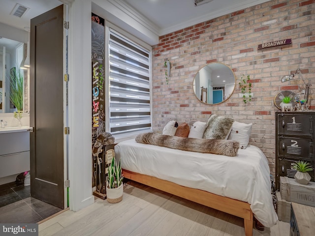 bedroom with ornamental molding, brick wall, and hardwood / wood-style floors