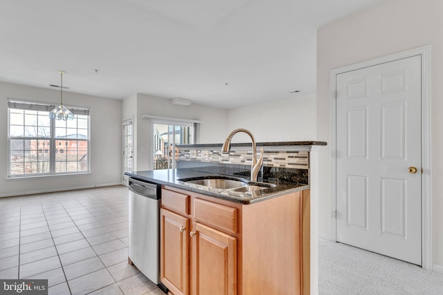 kitchen with tasteful backsplash, light tile patterned floors, dark stone countertops, stainless steel dishwasher, and a sink