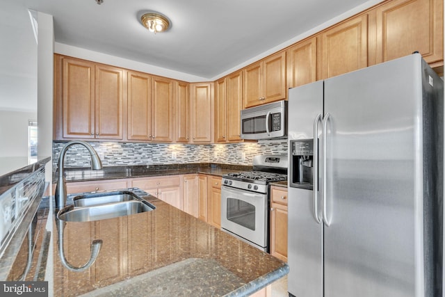 kitchen featuring backsplash, dark stone countertops, appliances with stainless steel finishes, and a sink