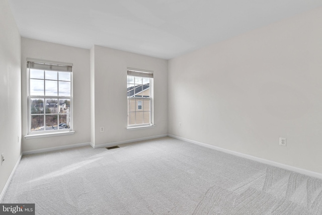 spare room featuring carpet flooring, visible vents, and baseboards