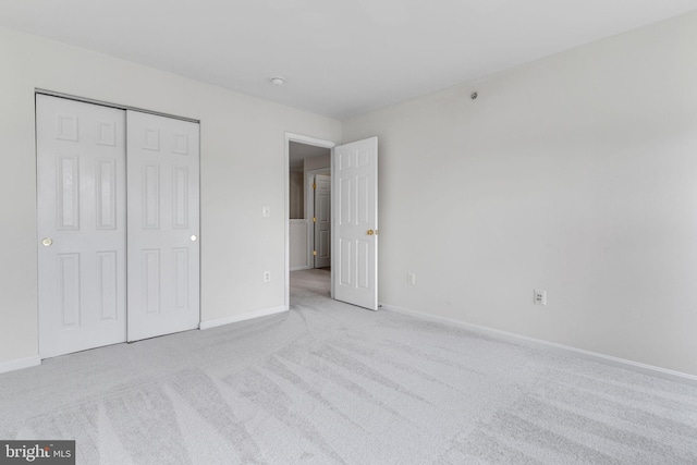 unfurnished bedroom featuring carpet, baseboards, and a closet