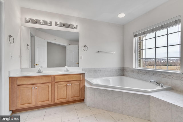 bathroom with tile patterned floors, double vanity, a bath, and a sink