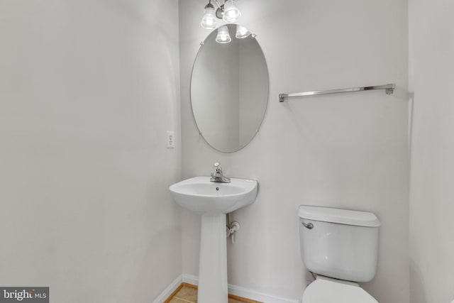 half bathroom featuring toilet, baseboards, and a sink