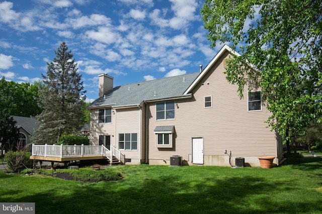 back of property with a deck, a chimney, a yard, and central air condition unit