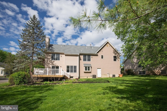 back of property featuring a lawn, a wooden deck, a chimney, and central AC