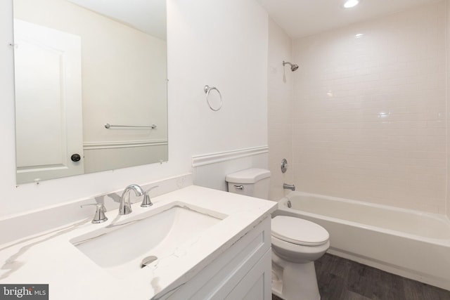 bathroom with toilet, wood finished floors,  shower combination, vanity, and recessed lighting