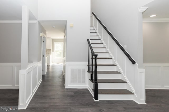 staircase with a decorative wall, crown molding, a wainscoted wall, and wood finished floors