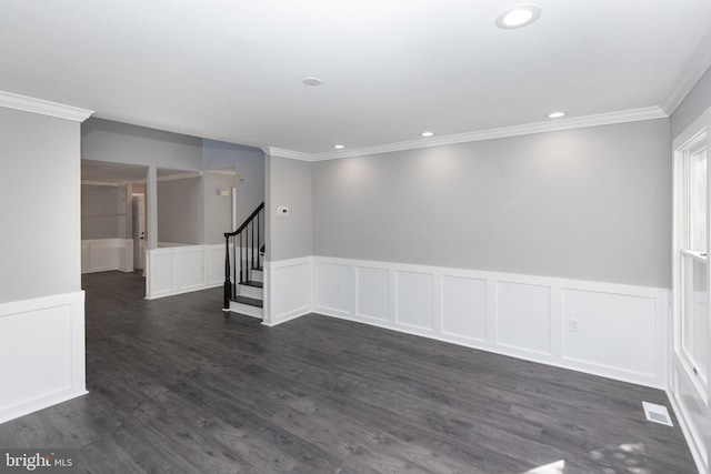 unfurnished room with a decorative wall, crown molding, stairway, dark wood-type flooring, and a wainscoted wall