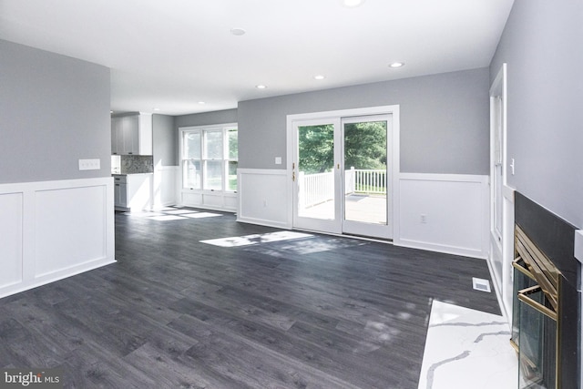 unfurnished living room with a wainscoted wall, dark wood-type flooring, recessed lighting, and a decorative wall