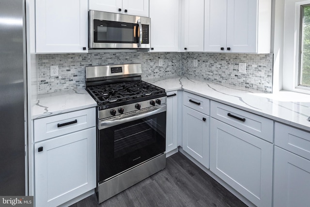 kitchen with stainless steel appliances, dark wood-type flooring, white cabinetry, decorative backsplash, and light stone countertops