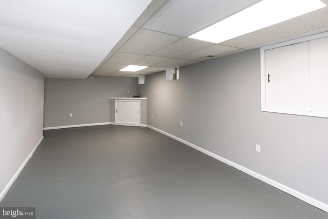 finished basement featuring baseboards and a drop ceiling