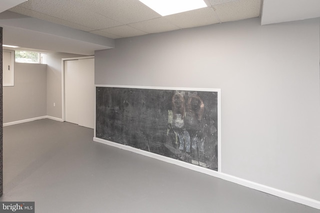 basement with a drop ceiling and baseboards