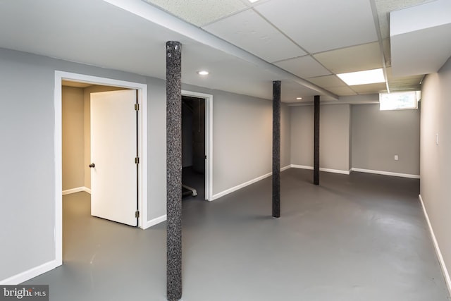 basement featuring baseboards, recessed lighting, and a drop ceiling