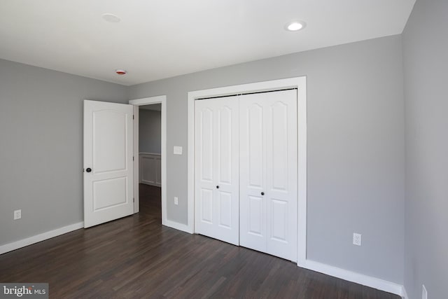 unfurnished bedroom with baseboards, dark wood-style floors, a closet, and recessed lighting