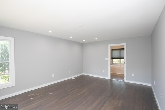 spare room with healthy amount of natural light, baseboards, dark wood-style flooring, and recessed lighting