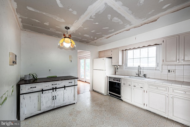 kitchen with sink, black dishwasher, white refrigerator, tile counters, and decorative backsplash