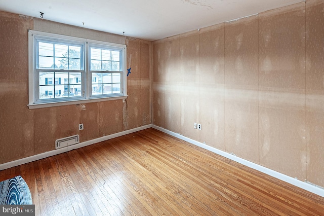 empty room with hardwood / wood-style flooring and wooden walls