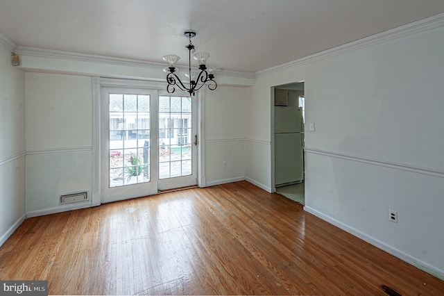 unfurnished dining area featuring ornamental molding, hardwood / wood-style floors, and a chandelier