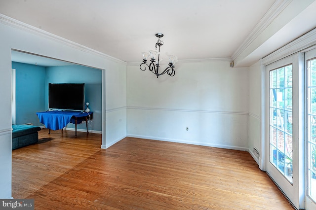 spare room featuring crown molding, a chandelier, and light wood-type flooring