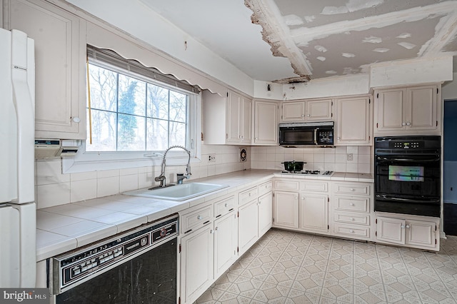 kitchen with sink, backsplash, tile counters, and black appliances