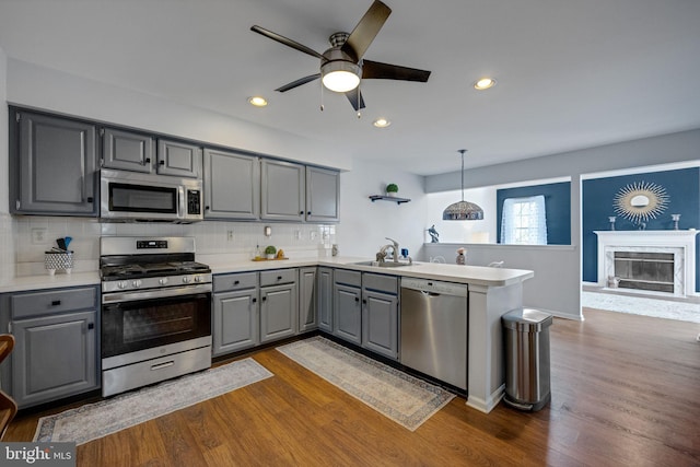 kitchen with pendant lighting, sink, gray cabinetry, stainless steel appliances, and kitchen peninsula