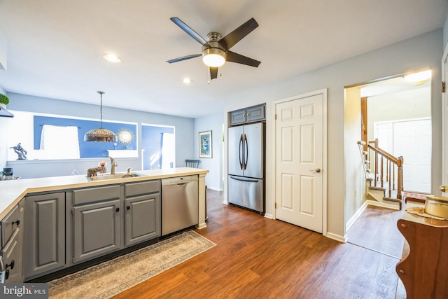 kitchen featuring pendant lighting, sink, gray cabinets, stainless steel appliances, and dark hardwood / wood-style flooring