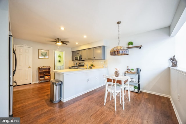 kitchen featuring gray cabinets, decorative light fixtures, dark hardwood / wood-style flooring, kitchen peninsula, and stainless steel appliances