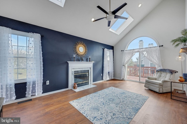 living room with hardwood / wood-style flooring, a healthy amount of sunlight, a fireplace, and a skylight