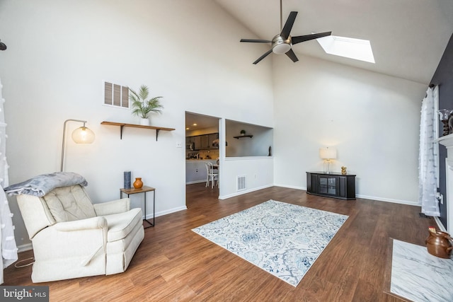 living room featuring ceiling fan, vaulted ceiling with skylight, and dark hardwood / wood-style flooring