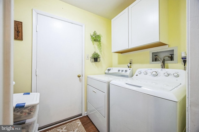 clothes washing area featuring washer and clothes dryer, cabinets, and wood-type flooring