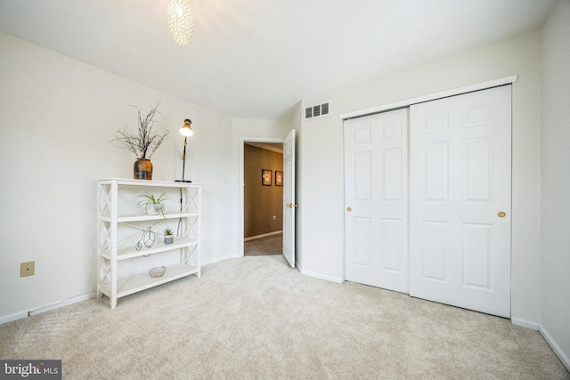 unfurnished bedroom featuring light colored carpet and a closet