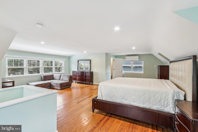 bedroom with lofted ceiling, hardwood / wood-style flooring, and a wall unit AC