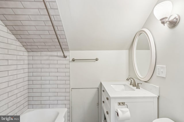 full bathroom featuring lofted ceiling, vanity, tiled shower / bath, and toilet