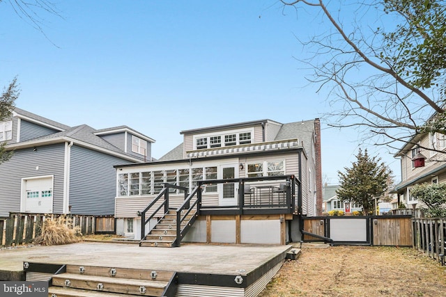 rear view of property featuring a wooden deck and a sunroom