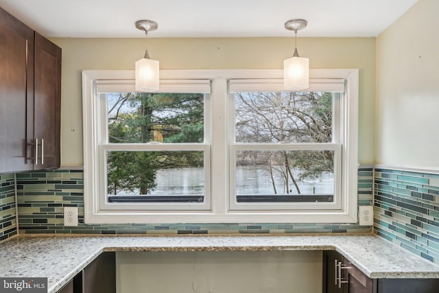 room details with dark brown cabinets, light stone counters, and decorative light fixtures